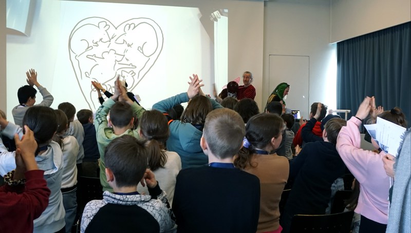 Foto vom Erzählfestival 2022. Lorenz Pauli erzählt eine Geschichte. Die Schülerinnen und Schüler beteiligen sich aktiv.
