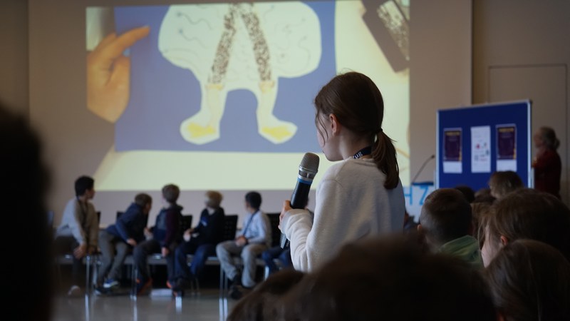 Ein Mädchen erzählt eine eigene Geschichte, ein selbstgemaltes Bild wird gezeigt