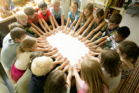 PH Zug Professur Mathematik: Kinder legen im Kreis ihre Hände auf den Tisch.