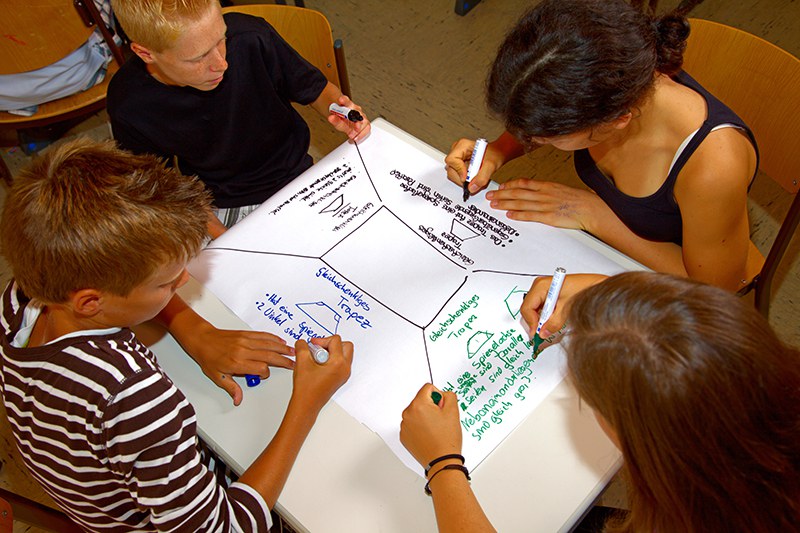 Schülerinnen und Schüler arbeiten zusammen an einer Aufgabe